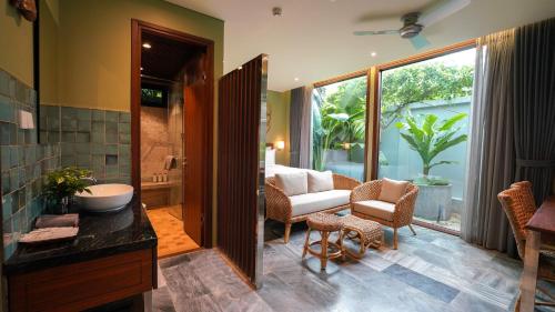 a bathroom with a tub and a sink in a room at CHiEM HoiAn - The Beachside Boutique Hotel & Villa in Hoi An