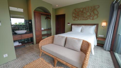 a bedroom with a bed and a chair and a bathroom at CHiEM HoiAn - The Beachside Boutique Hotel & Villa in Hoi An