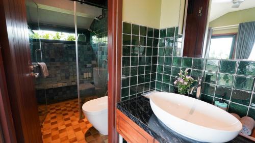 a green tiled bathroom with a sink and a toilet at CHiEM HoiAn - The Beachside Boutique Hotel & Villa in Hoi An