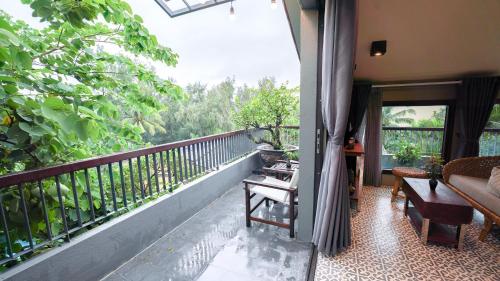 a balcony with a room with a view of trees at CHiEM HoiAn - The Beachside Boutique Hotel & Villa in Hoi An