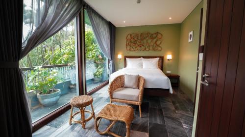 a bedroom with a bed and a chair and a window at CHiEM HoiAn - The Beachside Boutique Hotel & Villa in Hoi An