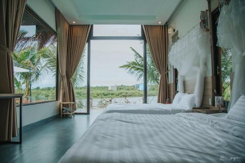 ein Schlafzimmer mit einem großen Bett und einem großen Fenster in der Unterkunft Emo Coffee Home - Venuestay in Dak Lak