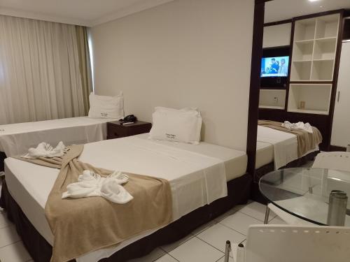 two beds in a hotel room with towels on them at PONTA NEGRA FLAT APART in Natal