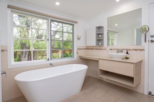 a bathroom with a tub and a sink and a window at Summer Cottage in Dunsborough