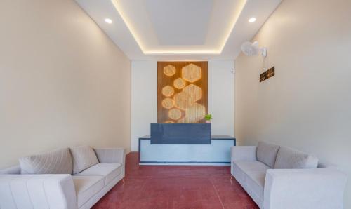 a living room with two white couches and a painting at Itsy Hotels Greenland Jungle View in Bhubaneshwar