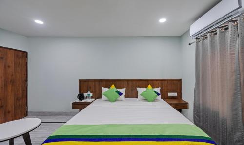 a bedroom with a large bed with green and yellow pillows at Itsy Hotels Greenland Jungle View in Bhubaneshwar