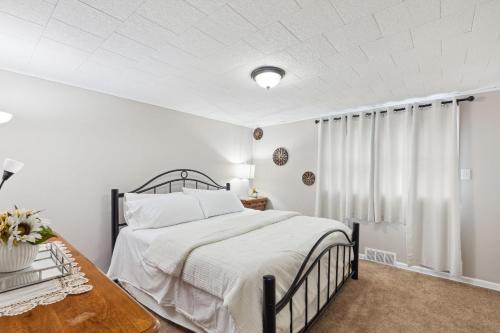 a white bedroom with a bed and a table at Charming Glenolden Townhouse in Glenolden