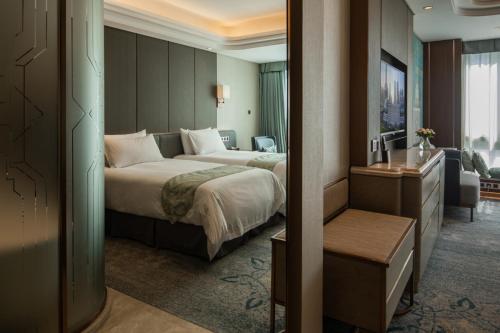 a hotel room with two beds and a television at Oriental Riverside Bund View Hotel (Shanghai International Convention Center) in Shanghai