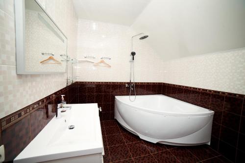 y baño con bañera blanca y lavamanos. en Alexandrovskaya Sloboda Hotel, en Pervoye Maya