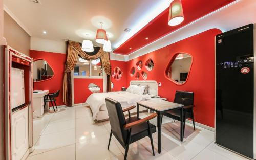 a bedroom with red walls and a bed and a table at Olle Business Hotel in Gwangju