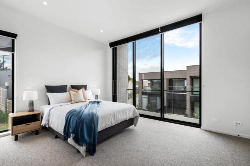 een slaapkamer met een bed en grote ramen bij 3brm townhouse close to Geelong CBD in Geelong West
