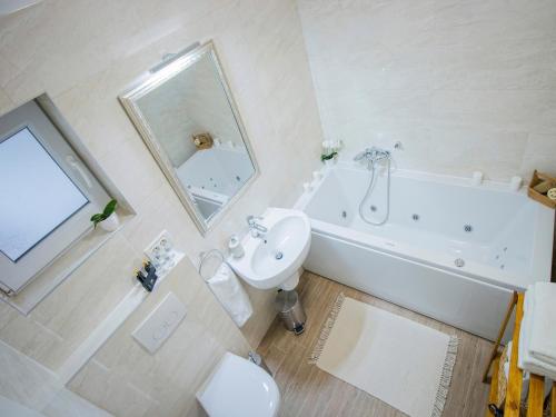 a white bathroom with a tub and a sink at Holiday Home Lukica in Privlaka