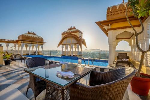 a patio with a table and chairs and a pool at Sterling Balicha Udaipur in Udaipur