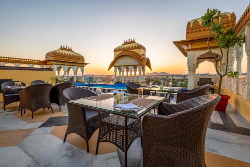 a patio with tables and chairs on a balcony at Sterling Balicha Udaipur in Udaipur