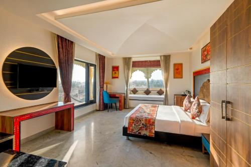 a hotel room with a bed and a television at Sterling Balicha Udaipur in Udaipur