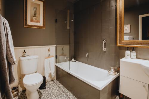 a bathroom with a toilet and a tub and a sink at Elegant apartment with balcony and free parking in Melbourne