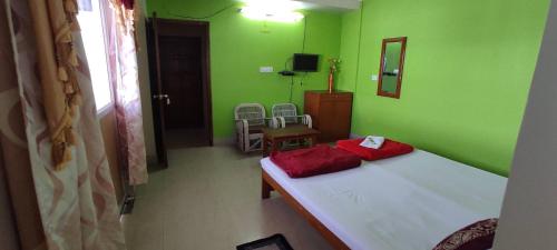 a bedroom with green walls and a bed with red pillows at Pine Shillong Guest House in Shillong