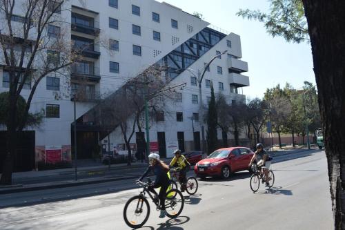 Tres personas montando bicicletas por una calle con un edificio en Right @Reforma - Beautiful condo with 2 balconies en Ciudad de México
