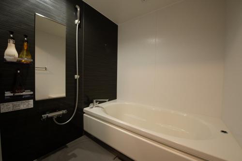 - białą wannę w łazience z lustrem w obiekcie HIYORI-STAY MatsueBiyori - Vacation STAY 46648v w mieście Matsue