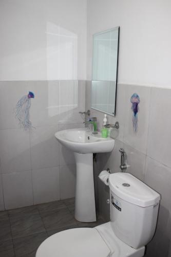 La salle de bains blanche est pourvue de toilettes et d'un lavabo. dans l'établissement Olideb Gedara, à Negombo