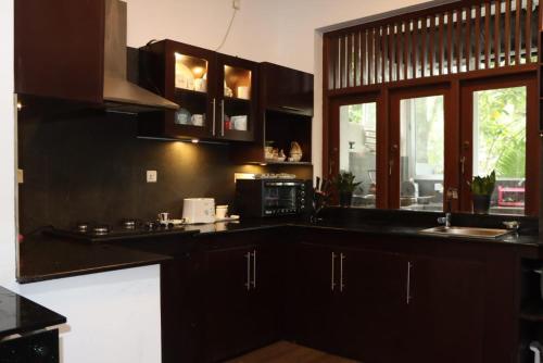 a kitchen with black cabinets and a microwave at Gampaha Heritage in Gampaha