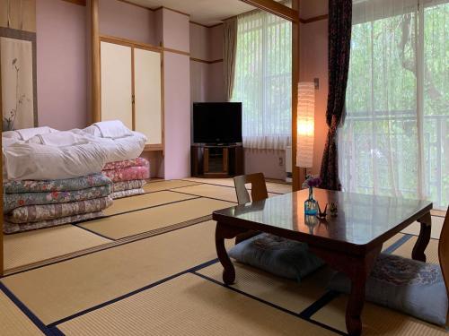 a living room with a table and a tv at Guestroom Garden Azumino in Azumino
