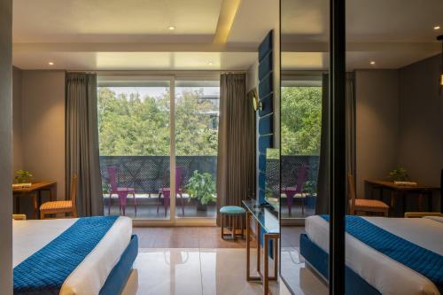 Habitación de hotel con 2 camas y balcón en The Aldott Cyber City, en Gurgaon