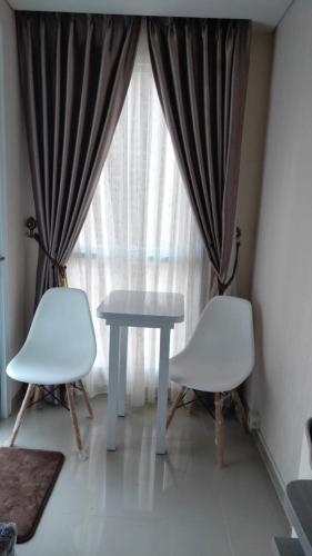 2 sillas blancas y una mesa frente a una ventana en Apartemen Skylounge Makassar, en Mandai