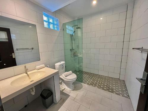 y baño con aseo, lavabo y ducha. en CG Guesthouse Canggu en Canggu