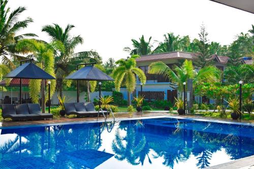 una piscina con sillas y sombrillas junto a una casa en Hotel Green Garden, en Trincomalee