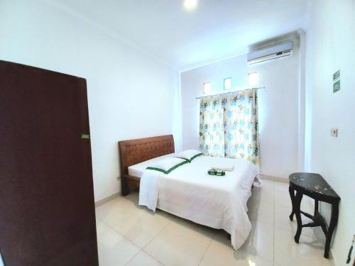 a bedroom with a bed and a table and a window at Homestay Jogja dekat Malioboro by Simply Homy in Yogyakarta