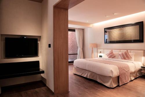 a bedroom with a large bed and a flat screen tv at Brightland Resort & Spa in Mahabaleshwar