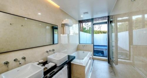 a bathroom with a sink and a tub and a mirror at The Shimpang Spa & Poolvilla in Seogwipo