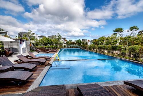 a large swimming pool with lounge chairs on a deck at The Shimpang Spa & Poolvilla in Seogwipo