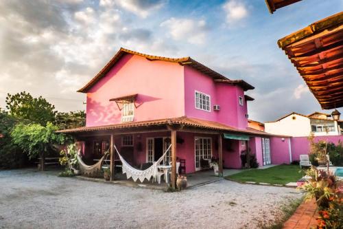 uma casa rosa com uma rede em frente em Suítes casa rosada em Cabo Frio