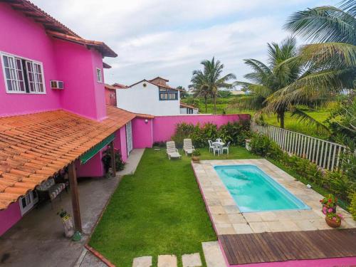 uma casa cor-de-rosa com uma piscina no quintal em Suítes casa rosada em Cabo Frio