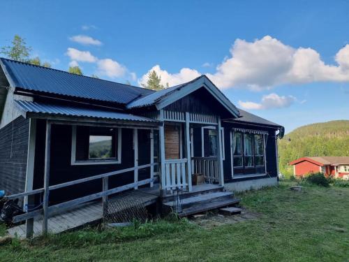 a small black house with a porch on a field at Rustikales Hexenhäuschen in Stöde