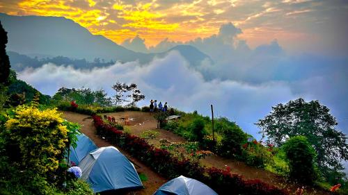 a group of people standing next to tents on a mountain at Munnar Tent Camping in Munnar