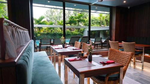 a restaurant with tables and chairs and large windows at CHiEM HoiAn - The Beachside Boutique Hotel & Villa in Hoi An