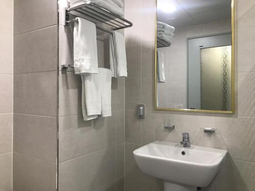 a white bathroom with a sink and a mirror at Primula Hotel - Formerly Sanbangsan Hotel in Seogwipo