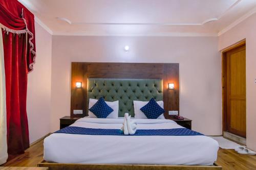 a bedroom with a large white bed with blue pillows at FabHotel The Moon in Manāli