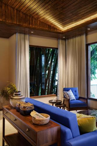 a living room with a blue couch and a table at Anand Kashi by the Ganges Rishikesh - IHCL Seleqtions in Rishīkesh