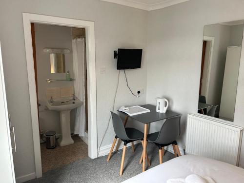 a room with a table and chairs and a sink at The Clifton Seafront Hotel in Morecambe