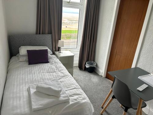a bedroom with a bed and a desk and a window at The Clifton Seafront Hotel in Morecambe