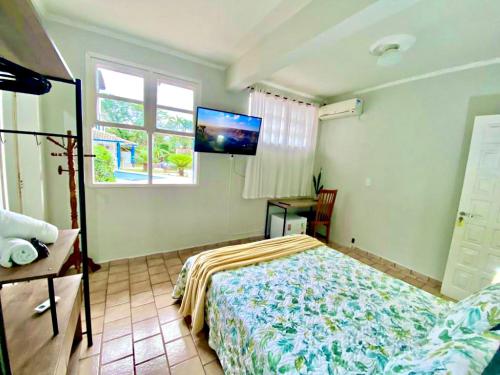 a bedroom with a bed and a flat screen tv at Garden 437 Suítes in Florianópolis
