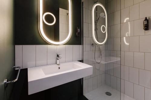 a bathroom with a sink and two mirrors at ibis Lyon Est Meyzieu in Meyzieu