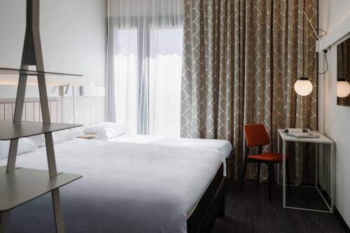 a hotel room with a bed and a window at ibis Lyon Est Meyzieu in Meyzieu