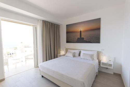 a white bedroom with a bed and a large window at Est hotel in Santa Cesarea Terme