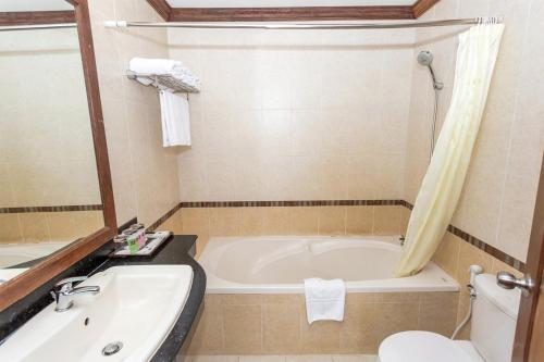 a bathroom with a tub and a toilet and a sink at Cheathata CTA Hotel Siem Reap in Siem Reap