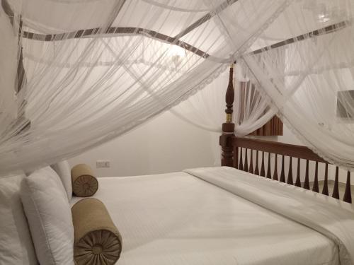 a bedroom with a canopy bed with white drapes at Luxury Villa with BB Free WI-FI in Bentota